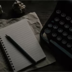 A typewriter, notepad, and crumpled paper are shown.